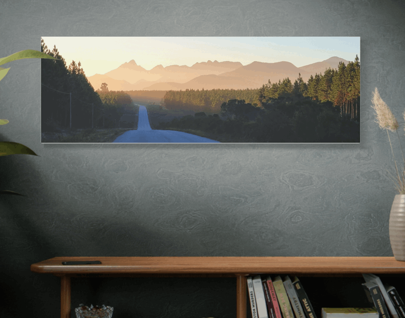 Photo print of a road cutting through the forests with mountains in the distance